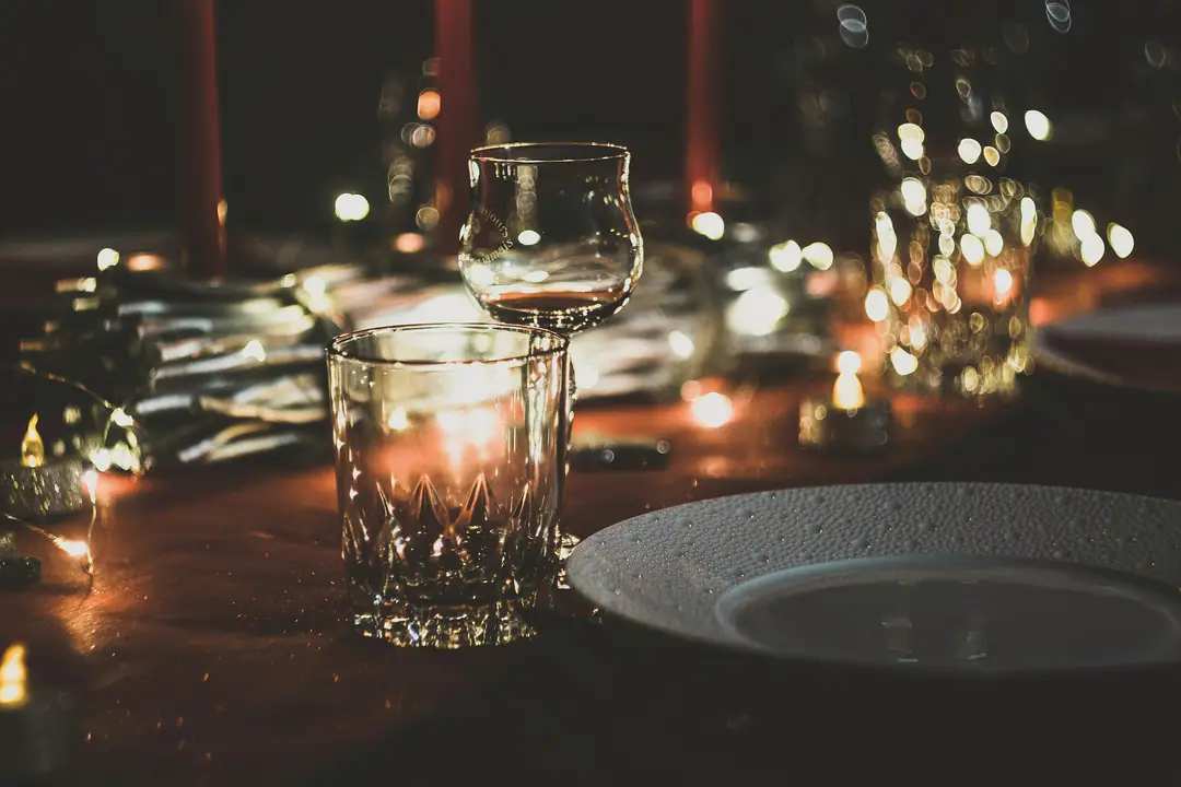 Taça e prato numa mesa escura, iluminada por velas